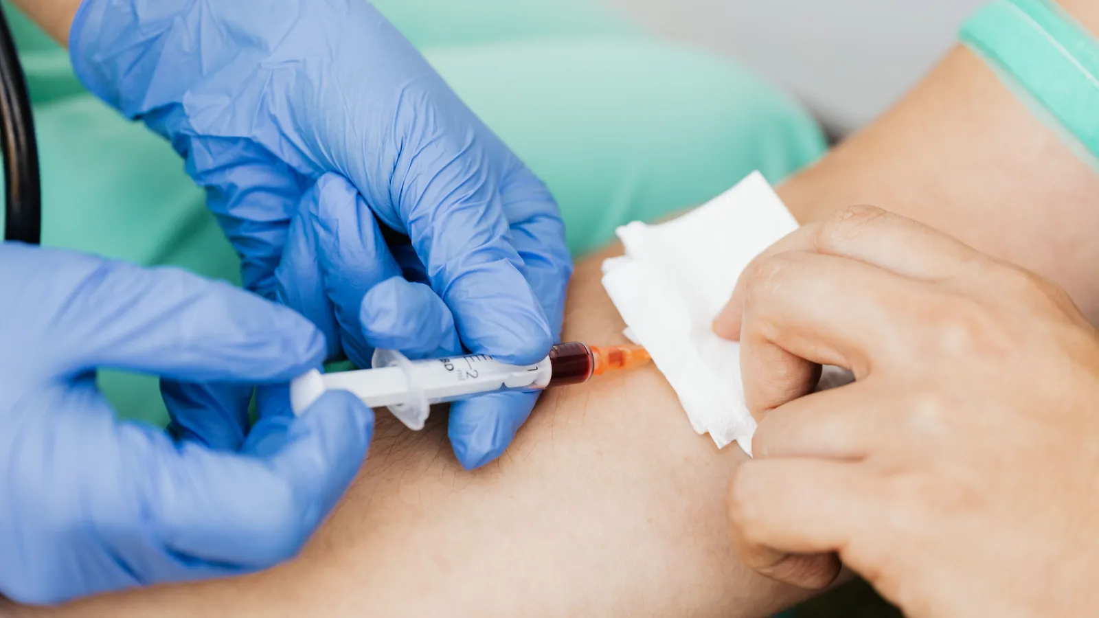 A nurse in blue gloves drawing a baseline blood sample from a patient